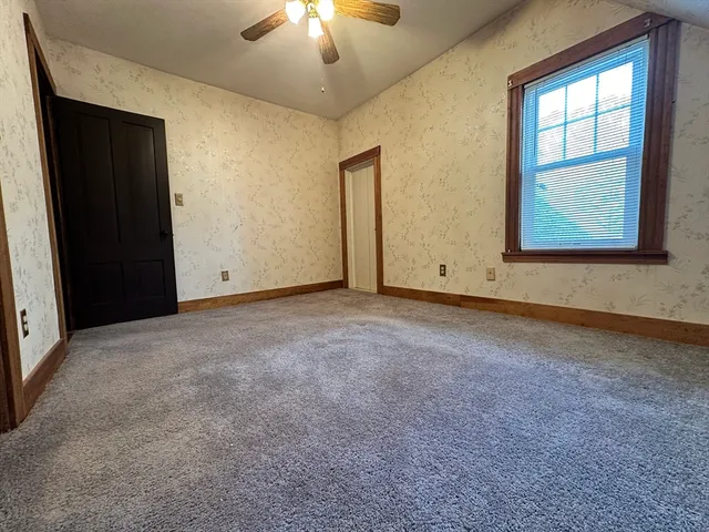 an empty room with windows and chandelier fan