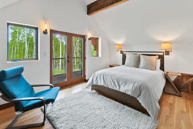 a bedroom with a bed a table and windows