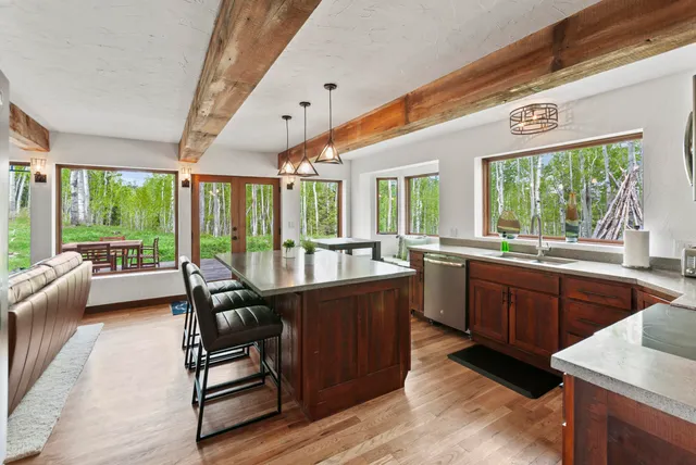 a open kitchen with stainless steel appliances granite countertop a refrigerator a sink dishwasher a stove and a dining table with wooden floor