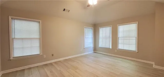 an empty room with wooden floor and windows