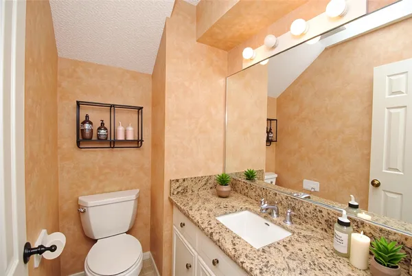 a bathroom with a granite countertop toilet sink and mirror