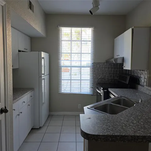 a kitchen with granite countertop a sink and a refrigerator