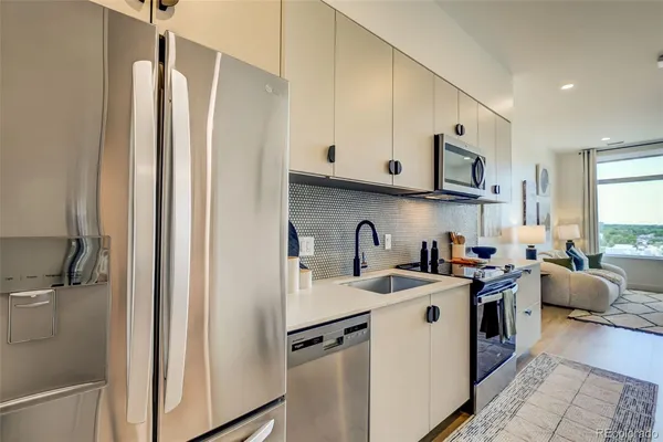 a kitchen with stainless steel appliances a sink a stove a refrigerator cabinets and a window