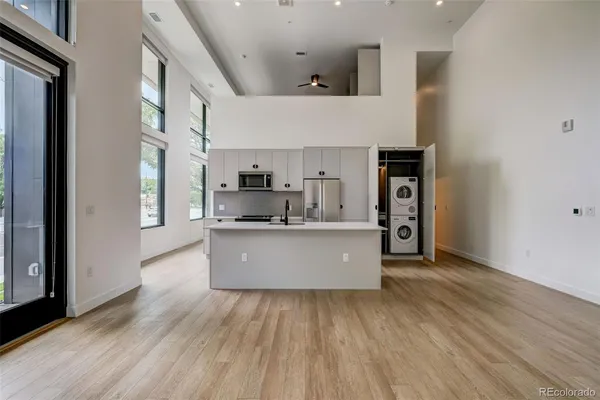 a large kitchen with stainless steel appliances a large counter top a wooden floors and a large window