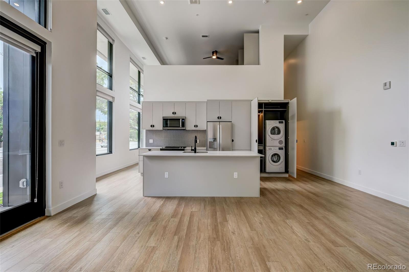 1521 Hooker Street, Unit 308 Denver, CO 80204 - Photo 9 of 31 a large kitchen with stainless steel appliances a large counter top a wooden floors and a large window
