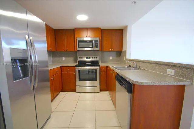 a kitchen with stainless steel appliances granite countertop a sink a stove a refrigerator and a microwave