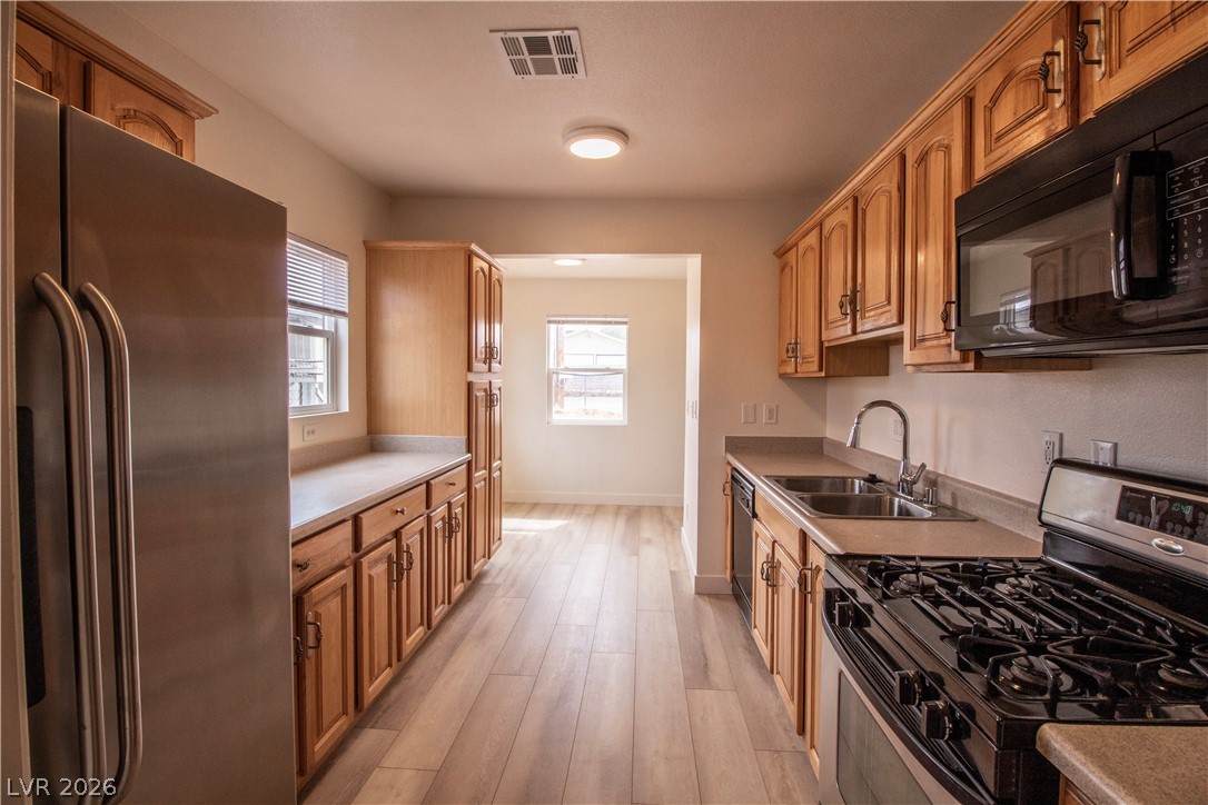 119 West Victory Road Henderson, NV 89015 - Photo 5 of 26 A galley kitchen awaits with natural wood cabinetry and resilient flooring.