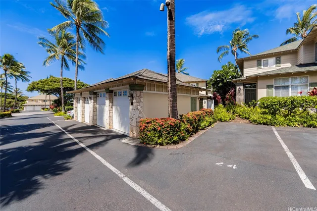 a front view of a house with a garden and palm trees