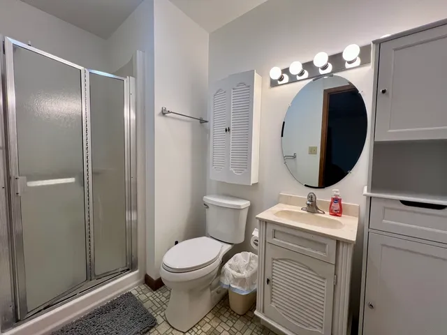 a bathroom with a toilet sink vanity granite and shower