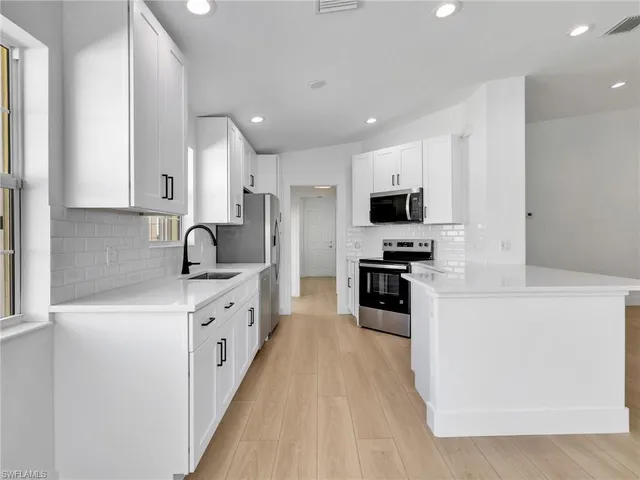 a kitchen with stainless steel appliances granite countertop a stove top oven a sink and a refrigerator