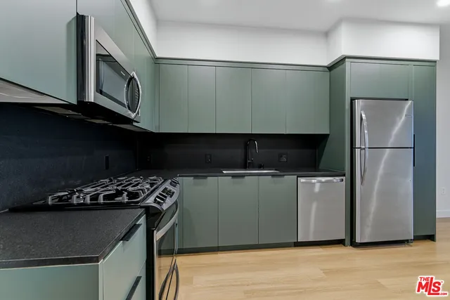 a kitchen with stainless steel appliances granite countertop a refrigerator and a stove