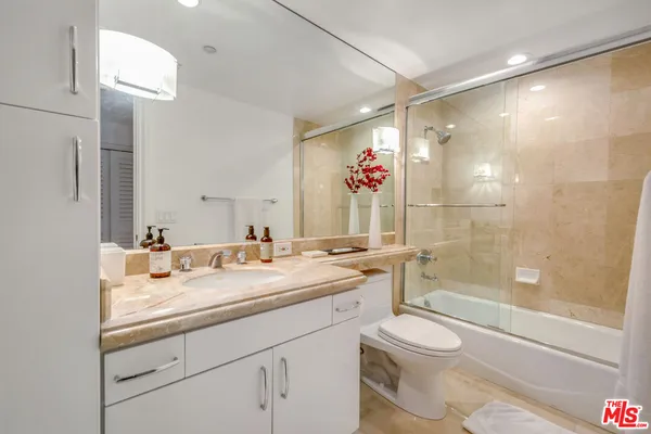 a bathroom with a granite countertop sink mirror vanity and toilet