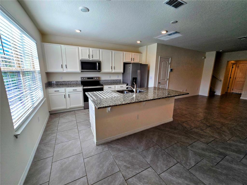17101 Water Spring Boulevard Winter Garden, FL 34787 - Photo 3 of 29 a large kitchen with stainless steel appliances granite countertop a stove a sink and a refrigerator