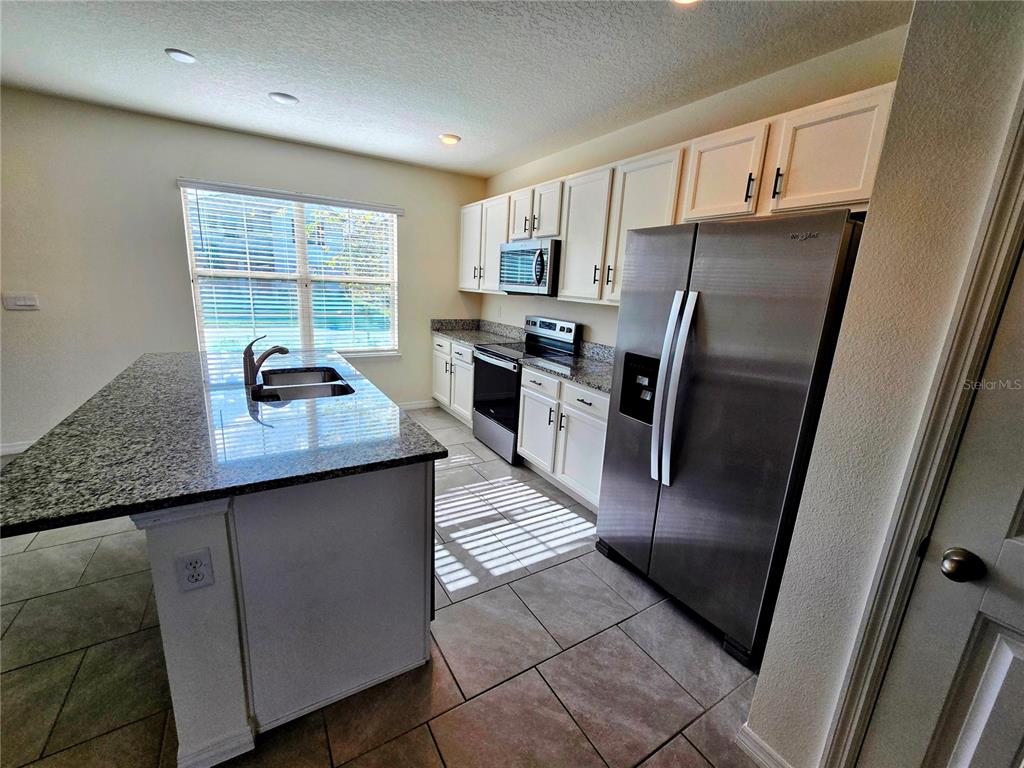 17101 Water Spring Boulevard Winter Garden, FL 34787 - Photo 5 of 29 a kitchen with stainless steel appliances granite countertop a refrigerator a sink a stove and island