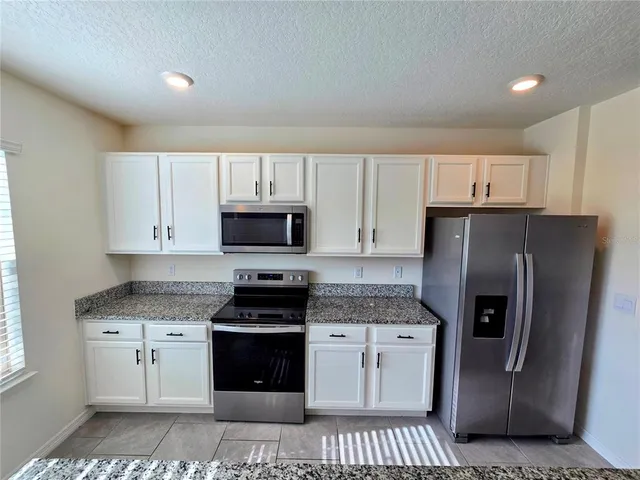 a kitchen with stainless steel appliances white cabinets and a refrigerator