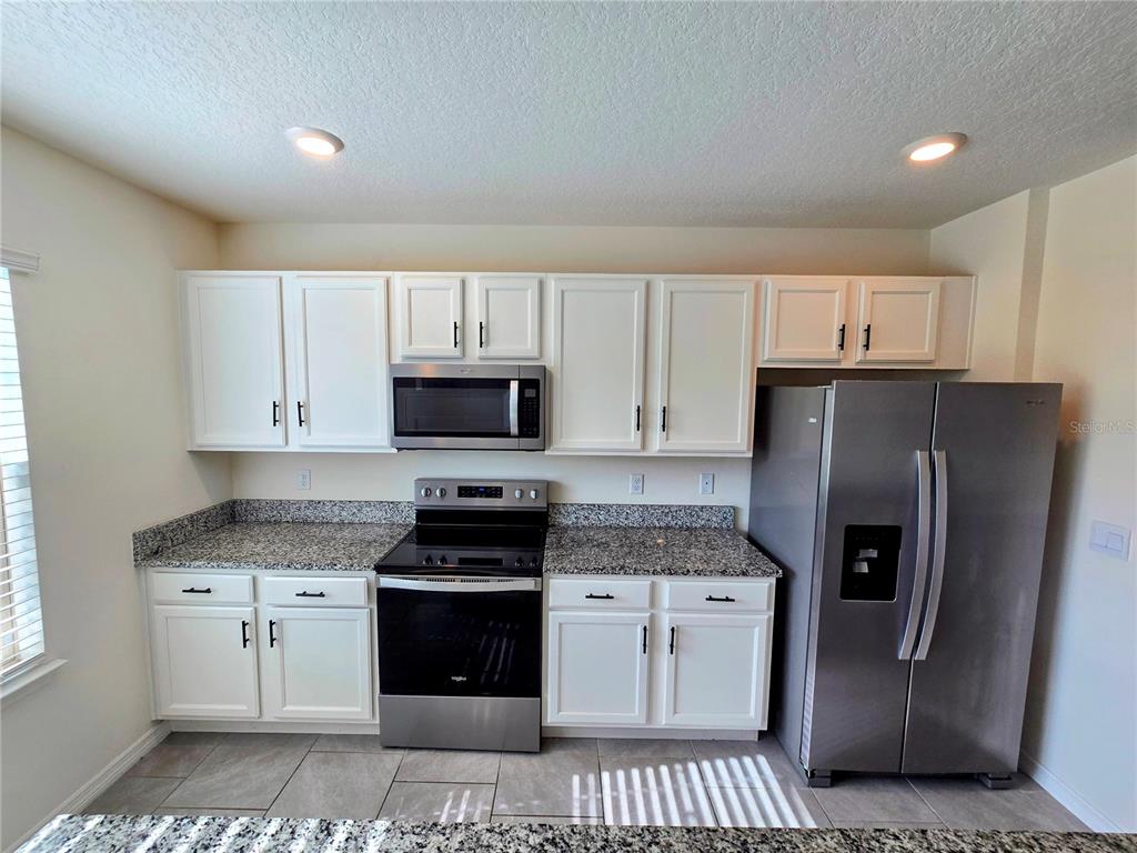 17101 Water Spring Boulevard Winter Garden, FL 34787 - Photo 6 of 29 a kitchen with stainless steel appliances white cabinets and a refrigerator