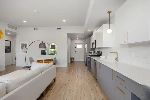 a large white kitchen with a large window a sink and stainless steel appliances