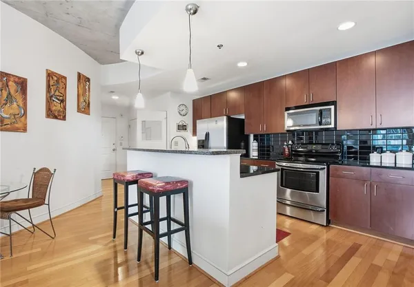 a kitchen with stainless steel appliances granite countertop a refrigerator a sink and wooden cabinets