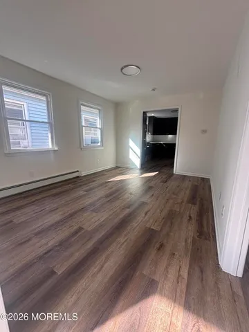 a view of empty room with wooden floor and window
