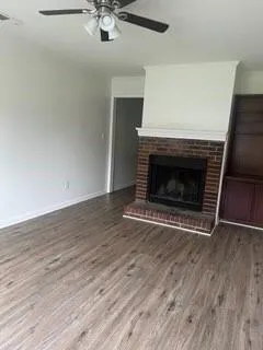 an empty room with wooden floor a fireplace and windows