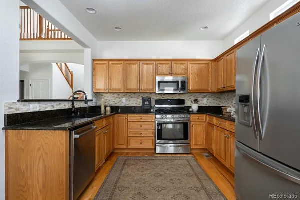 a kitchen with stainless steel appliances granite countertop a sink stove microwave and refrigerator