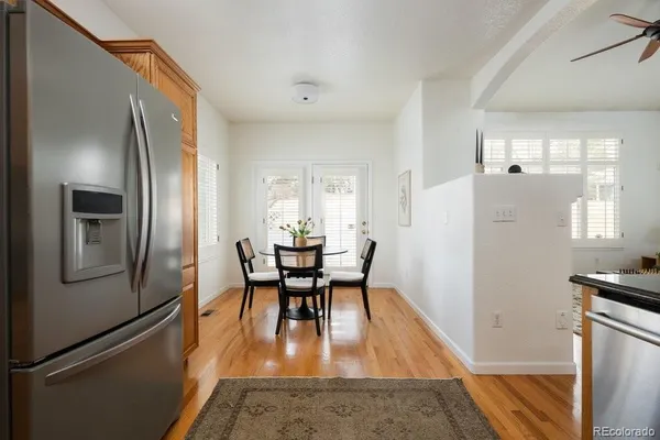 a dining room with stainless steel appliances granite countertop furniture a refrigerator a kitchen island a stove and a refrigerator with wooden floor
