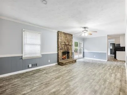 a view of an empty room with a fireplace and chandelier fan