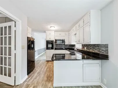 a kitchen that has a lot of cabinets a sink and appliances