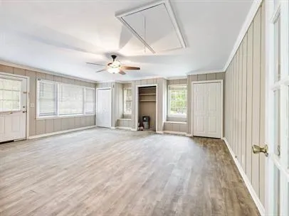 an empty room with wooden floor cabinet and windows