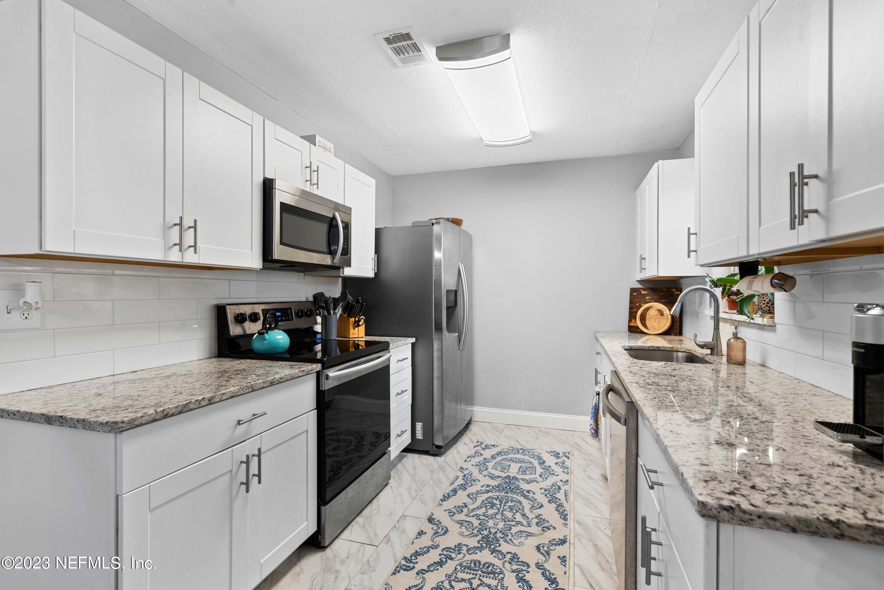 511 Gerona Road St. Augustine, FL 32086 - Photo 9 of 30 a kitchen with stainless steel appliances granite countertop a sink stove refrigerator and cabinets