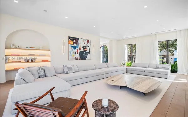 a kitchen with stainless steel appliances kitchen island granite countertop a refrigerator a sink a dining table and chairs with wooden floor