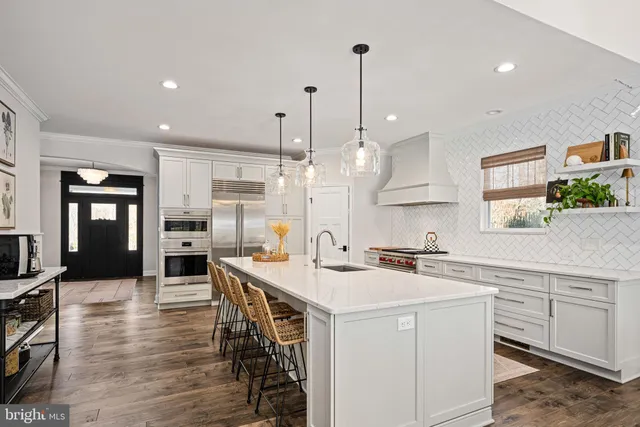 a kitchen with stainless steel appliances kitchen island a white table chairs sink and cabinets