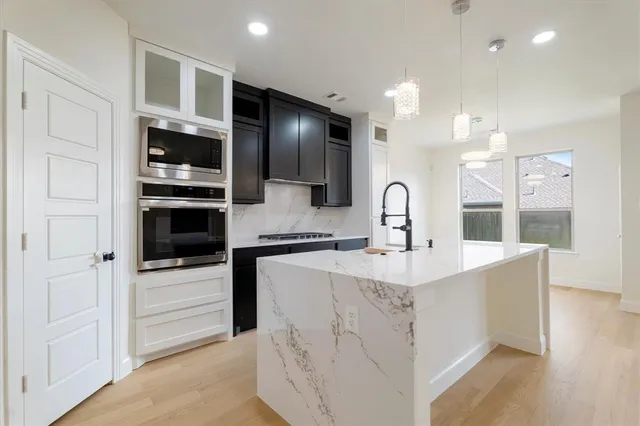 a kitchen with stainless steel appliances kitchen island granite countertop a sink a stove and refrigerator