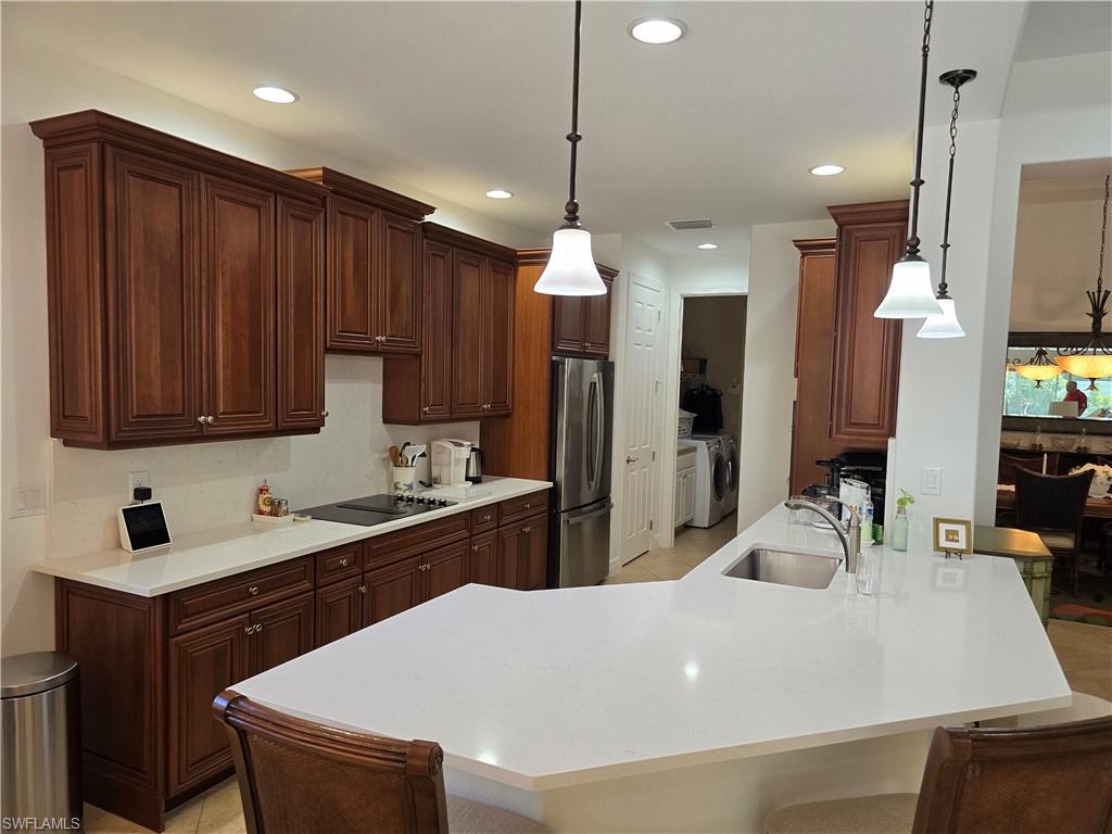 7887 Martino Circle Naples, FL 34112 - Photo 7 of 25 a kitchen with a sink a refrigerator and wooden cabinets