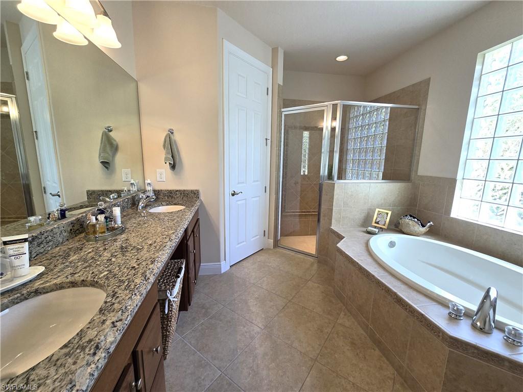 7887 Martino Circle Naples, FL 34112 - Photo 10 of 25 a bathroom with a granite countertop double vanity sink and a bathtub
