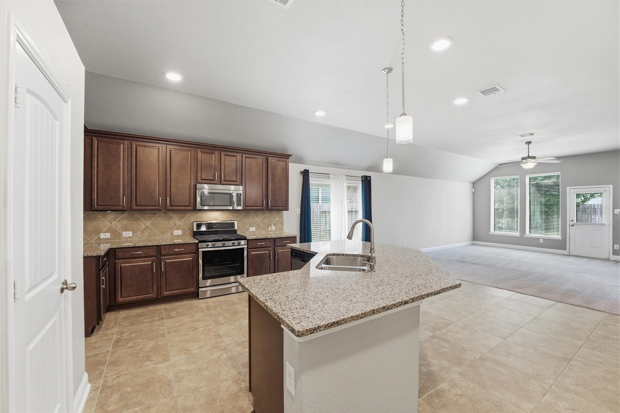 1911 Cedar Ridge Lane Pearland, TX 77089 - Photo 9 of 33 Island kitchen with granite counters, tile backsplash, 42 inch cabinets, and stainless steel appliances.