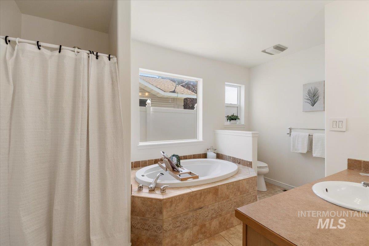 2032 Talus Loop Twin Falls, ID 83301 - Photo 35 of 43 Bathroom featuring a built-in soaking tub with tile surround, a spacious vanity with an integrated sink, a separate shower area, and multiple windows