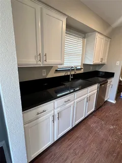 a kitchen with granite countertop white cabinets and sink