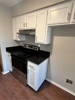 a kitchen with granite countertop a stove and a white cabinets