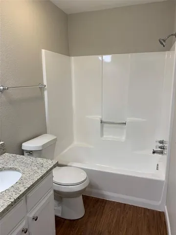 a bathroom with a granite countertop toilet and a sink