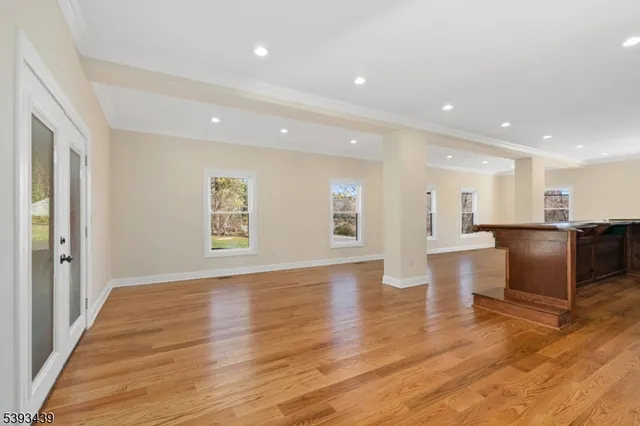 a view of an empty room with wooden floor and a kitchen