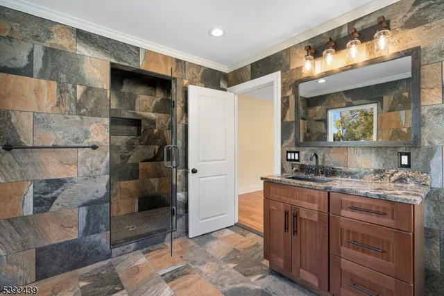 a bathroom with a granite countertop sink a mirror and a shower