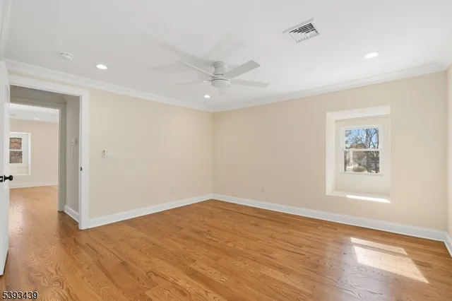 an empty room with wooden floor and ceiling fan