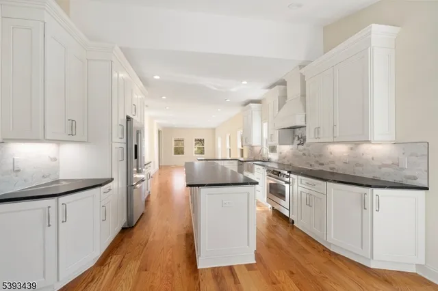 a large kitchen with stainless steel appliances granite countertop a lot of counter space and wooden floor