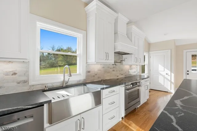 a kitchen with granite countertop a sink cabinets stainless steel appliances and a window