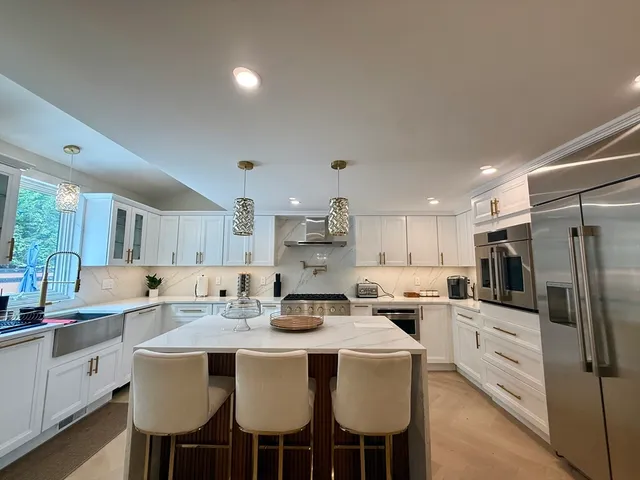 a kitchen with stainless steel appliances kitchen island granite countertop a sink refrigerator and cabinets