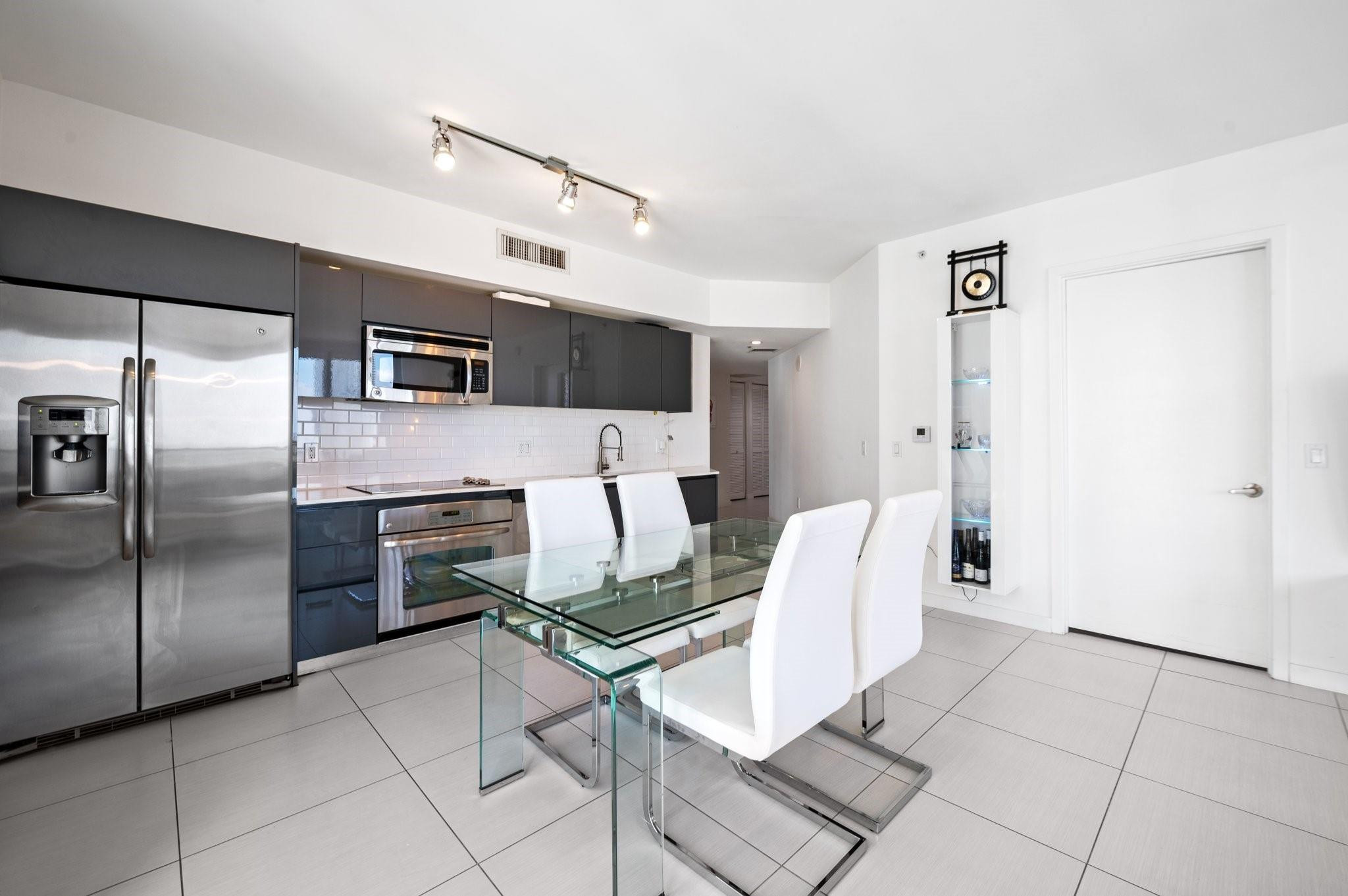 31 Southeast 6th Street, Unit 2002 Miami, FL 33131 - Photo 4 of 24 a kitchen with stainless steel appliances kitchen island granite countertop a refrigerator and a stove top oven