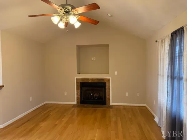 a view of empty room with a fireplace and wooden floor