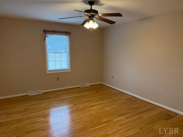 a view of an empty room with window and wooden floor