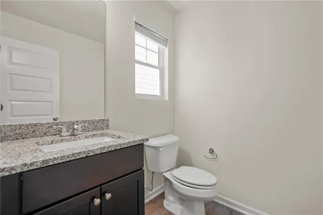 a bathroom with a granite countertop sink toilet and mirror